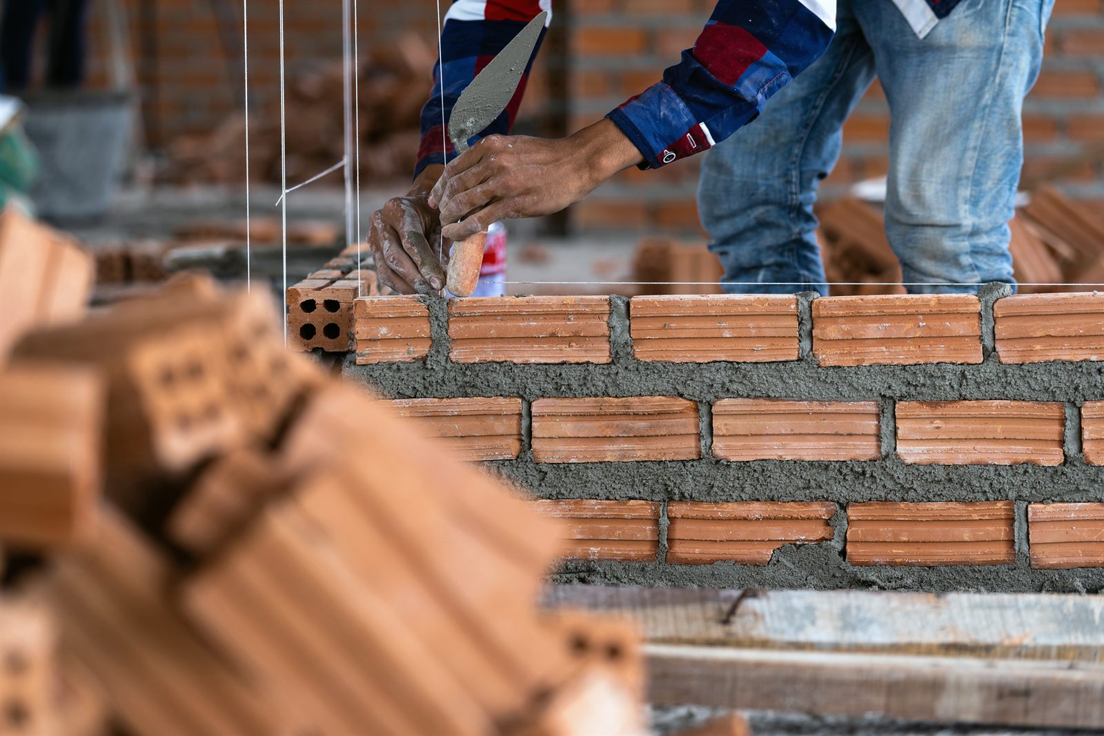 Albañil colocando tabique con mortero en la construcción de un muro